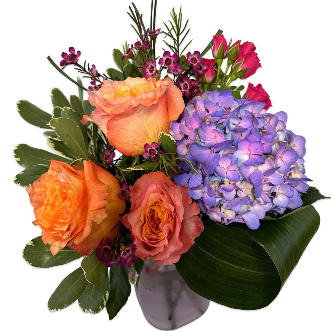 Colorful floral arrangement featuring orange roses, purple hydrangeas, and pink blooms with greenery.