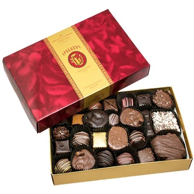 Gift box of gourmet chocolates in a red patterned lid, with neatly arranged assorted pieces inside.
