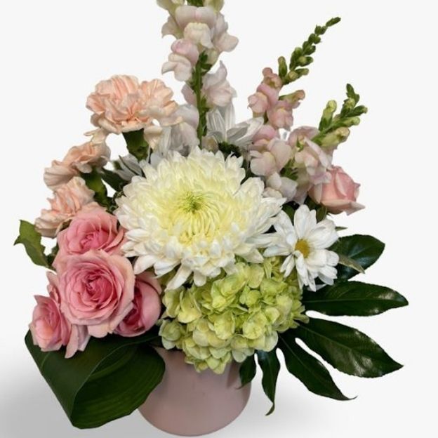 Elegant floral arrangement with pink roses, white chrysanthemums, daisies, and green hydrangeas in a pink vase.