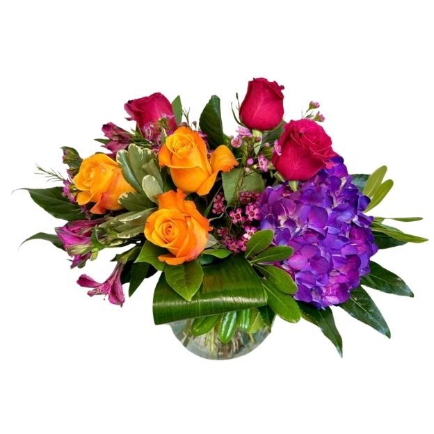 Vibrant bouquet of orange and fuchsia roses with purple hydrangea and alstroemeria in a low round vase.